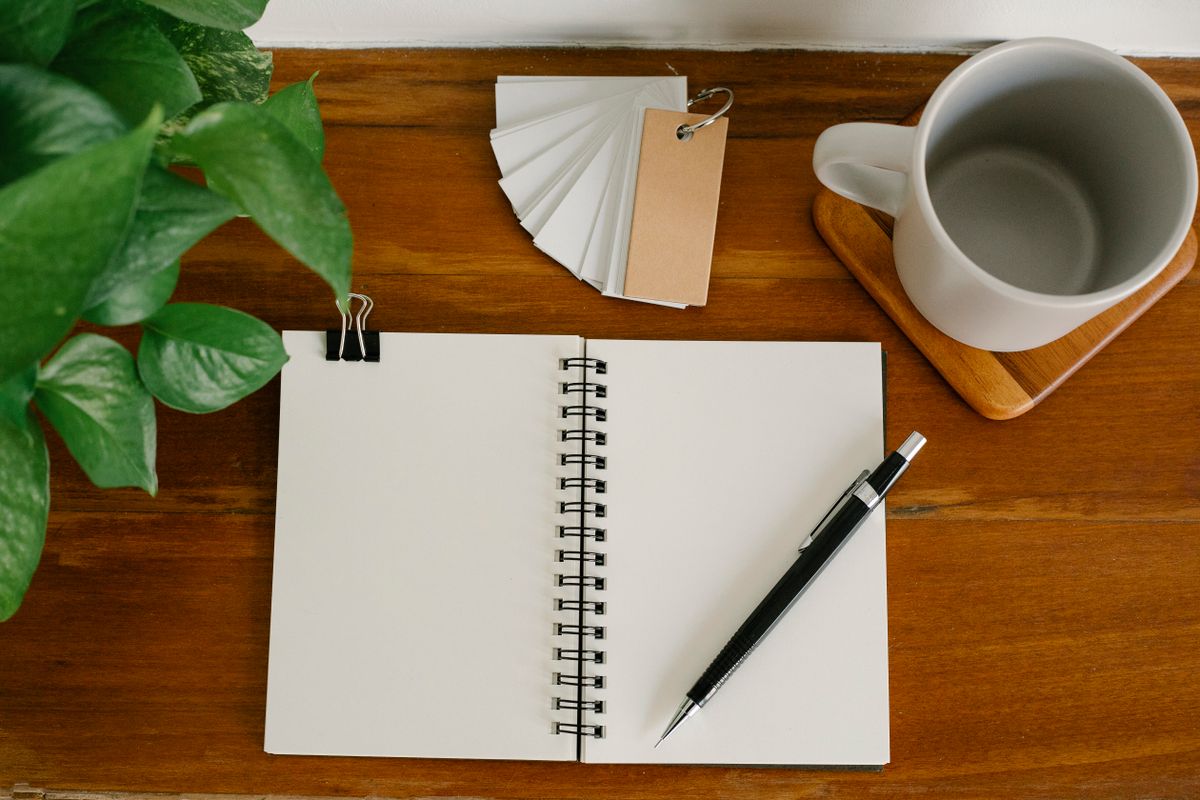 Taccuino, penna e tazza personalizzabili su una scrivania in legno