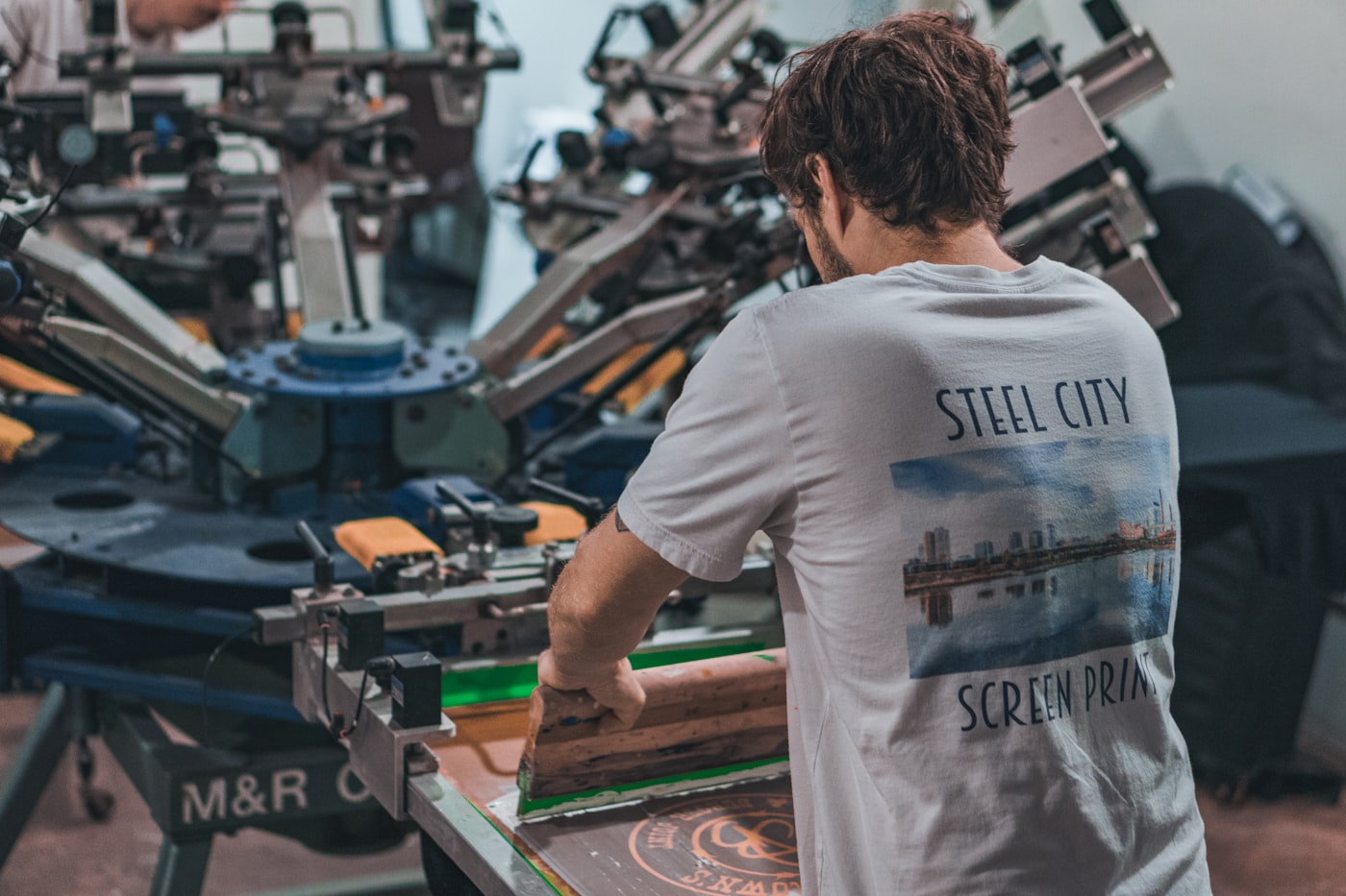 Operatore che stampa un logo su una maglietta con la macchina serigrafica